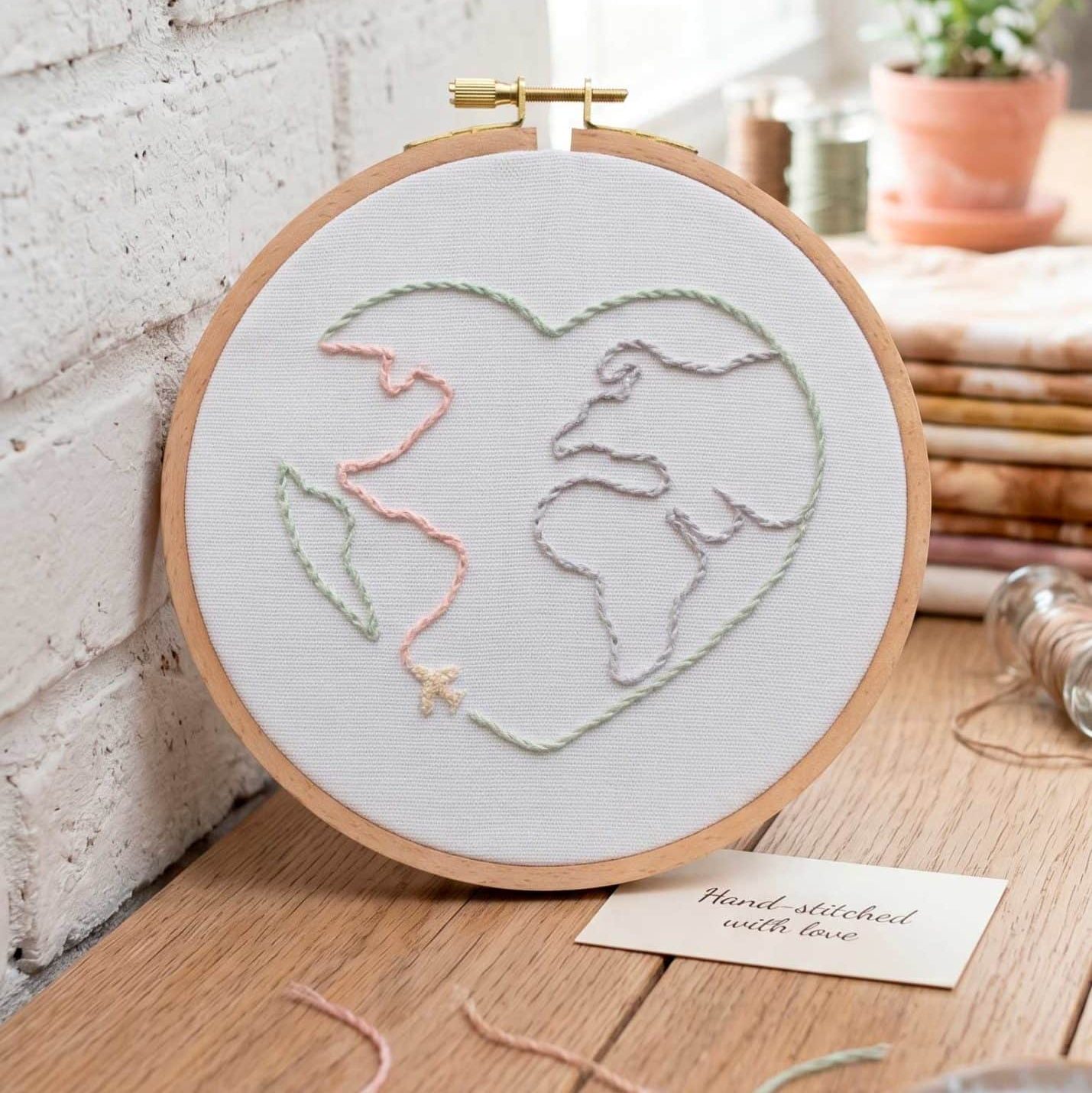 Love World embroidery displayed in a wooden hoop