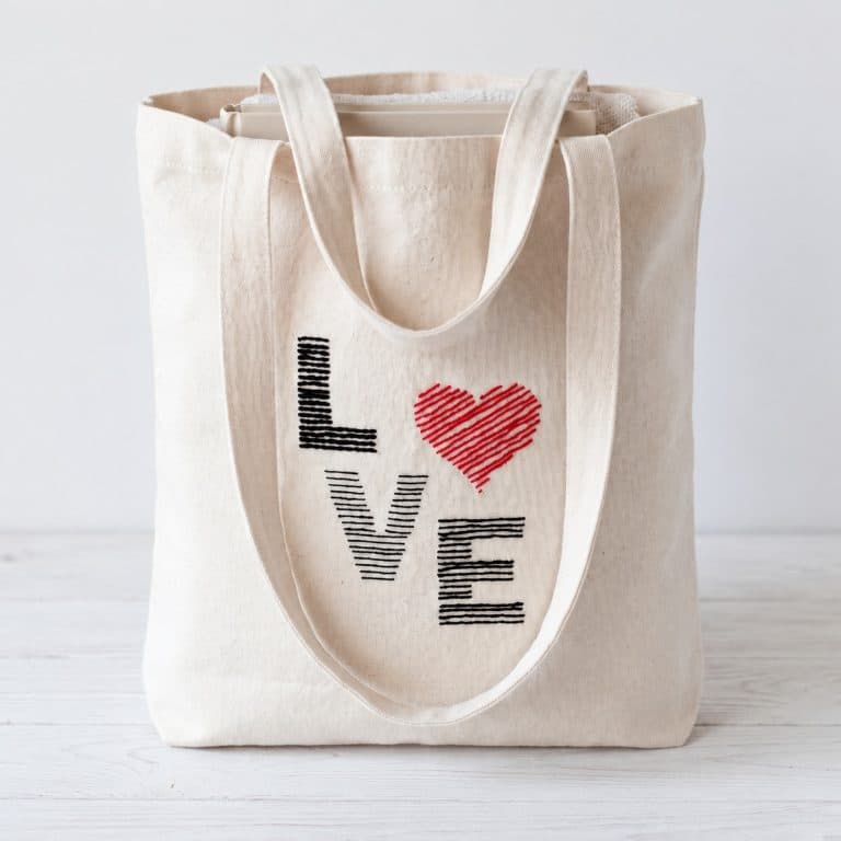 Natural cotton tote bag with LOVE lettering embroidered in black and a red heart