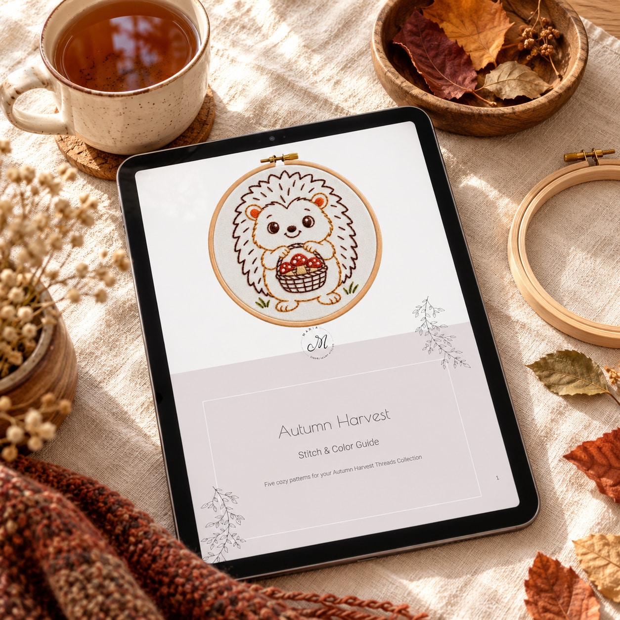 Autumn embroidery patterns: tablet showing the Autumn Harvest Stitch & Color Guide PDF cover, next to a cup of tea